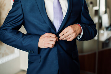 The groom is going to a dump in a suit and watch a tie with his hands