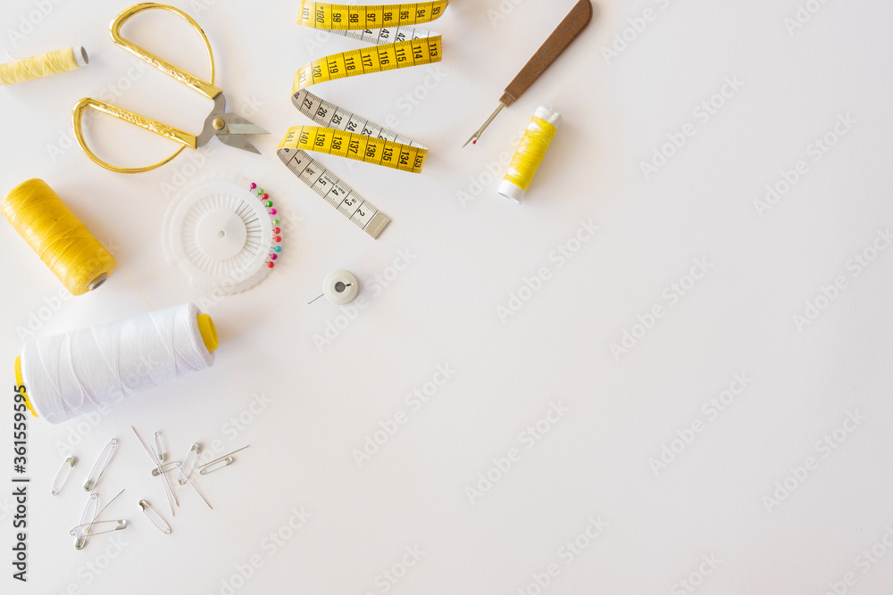 Wall mural Measuring tape, scissors and threads, tools for sewing, flat lay frame on a white background. Copy space