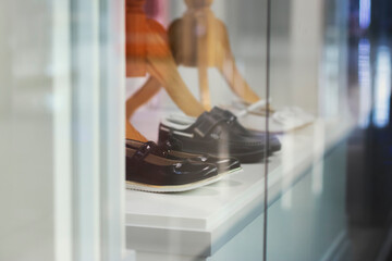 Three pairs of children's school shoes in a transparent display case of a clothing store. Preparing for the new school year.