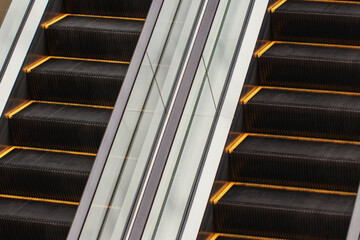 Large black escalator with yellow stripes and transparent railing in the shopping center building. The interior of a multi-storey store.