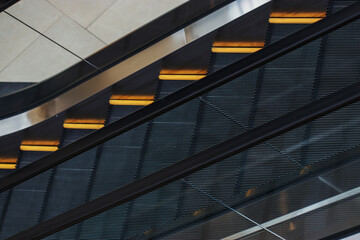 Obraz premium Large black escalator with yellow stripes and transparent railing in the shopping center building. The interior of a multi-storey store.