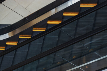 Large black escalator with yellow stripes and transparent railing in the shopping center building. The interior of a multi-storey store.