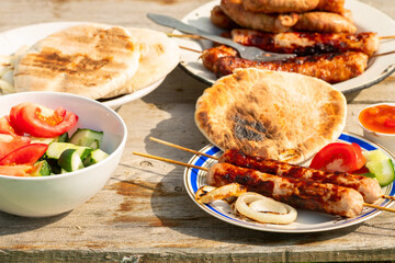 Barbecue sausages with fresh vegetables, fried onion sauce and tortillas . Lunch in nature