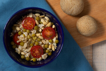 Arroz integral con tomate, porotos de soja y arvejas en un recipiente, concepto de comida saludable y vegana, vista desde arriba