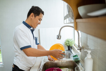 asian man washing the dishes in the kitchen at home