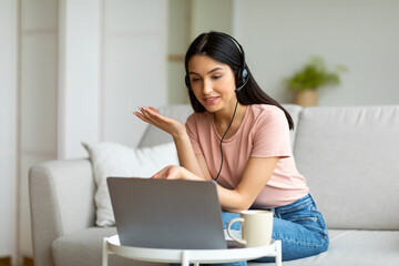 Girl Making Video Call Using Laptop Sitting On Couch Indoors