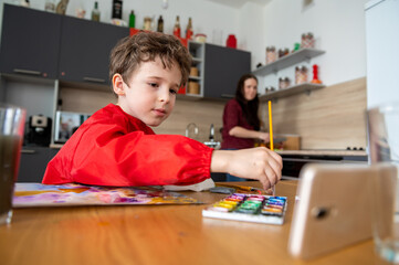 Boy draws painting wtith online distance lessons
