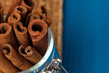 Cinnamon sticks in glass jar on blue wooden table