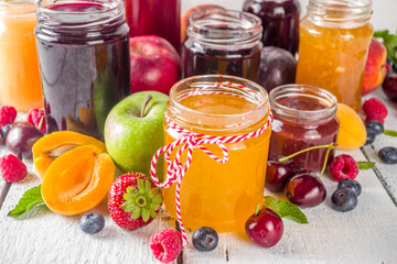 Assortment of berries and fruits jams. Set of various seasonal summer berry and fruit jam, marmalade and confitures. White wooden background copy space