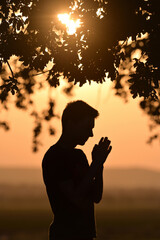 Portrait young man praying hands clasped