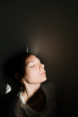 Girl sitting alone in sunlight pocket in dark room. mental health concept