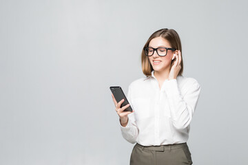 Fototapeta premium Young beautiful business woman talking via airpods wirrless headset holding phone isolated on white background