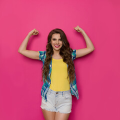 Strong Smiling Woman In Unbuttoned Lumberjack Shirt And Shorts Is Standing And Flexing Muscles