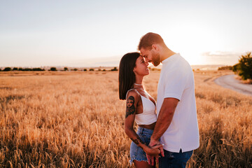 young couple holding hands in a yellow field at sunset. Love and Summer time