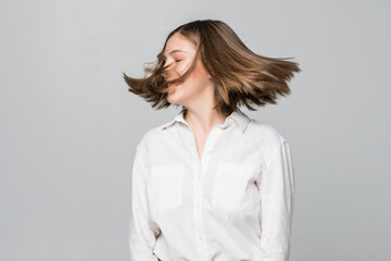 Young woman standing throwing hair up looking camera smiling playful isolated on white background