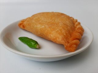 Pastel, is a pastry filled with chicken meat and mixed vegetable, then deep fried. Snack from Indonesia. On white plate. Isolated in white background.