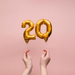Female hand holding a number 20 birthday anniversary celebration gold balloon