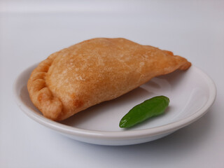 Pastel, is a pastry filled with chicken meat and mixed vegetable, then deep fried. Snack from Indonesia. On white plate. Isolated in white background.