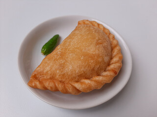 Pastel, is a pastry filled with chicken meat and mixed vegetable, then deep fried. Snack from Indonesia. On white plate. Isolated in white background.