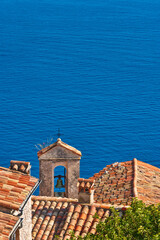 Terra cotta tile rooftops and bell tower of the Village of Eze with the Mediterranean Sea. French...