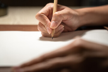 Handwriting on paper, people is using pencil to make at note on paperwork. Education/business action concept photo. Selective focus of pencil's part.