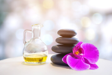bottle of aroma essential oil with candle and flower on stone table, spa concept.