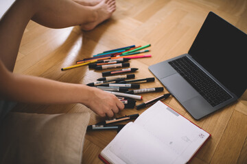 Anonymous female sitting on floor with laptop diary and tip markers