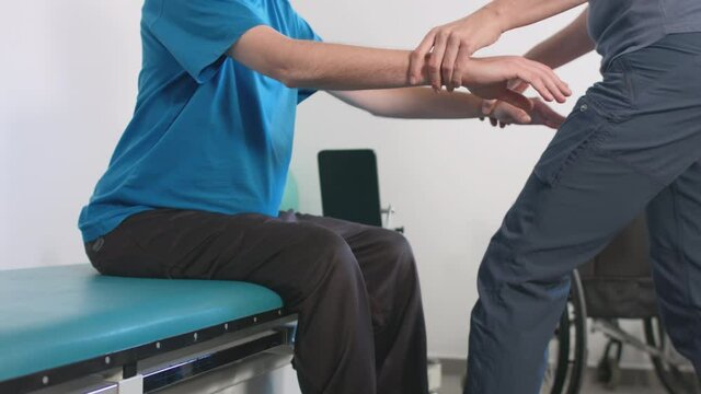 Physiotherapist exercising with disabled person on a therapy table.