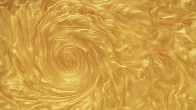 An undulating swirl of gold spangles in the water. Funnel with gold sequins mixing in the water, wavy abstract pattern