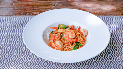 The spaghetti spicy shrimp in a white plate on the tablecloth.