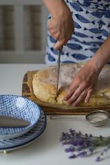 Woman cutting homemade traditional Greek pastry -- Bougatsa made with phyllo dough and semolina custard cream into pieces.