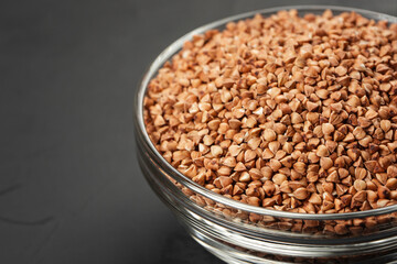 Glass container with buckwheat on a black background close-up.