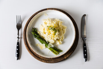 Creamy lemon risotto with parmesan and asparagus on white plate.