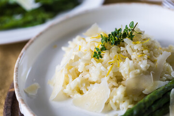 Creamy lemon risotto with parmesan and asparagus on white plate.