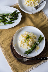 Creamy lemon risotto with parmesan and asparagus on white plate.