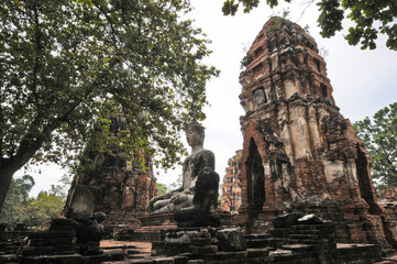 Vue sur les racines d'un arbre mokka, les feuilles vertes et les temples en briques rouges d' Ayuttaya, la ville sainte et ancienne capitale de la Tha&iuml;lande. Haut-lieu de tourisme pour le bouddhisme.