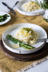 Creamy lemon risotto with parmesan and asparagus on white plate.