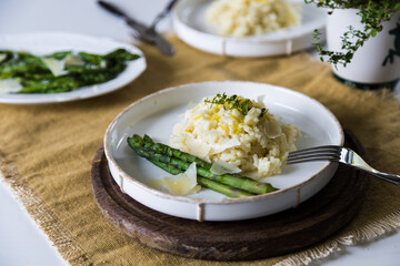 Creamy lemon risotto with parmesan and asparagus on white plate.