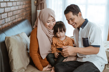 happiness of a Muslim family together when using a smartphone in the bedroom