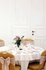 The festive table at the restaurant is decorated with candles and flowers. Wedding reception dinner. Wedding reception dinner. Tables served with candles and rose gold decor stands in restaurant. 