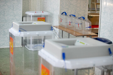Ballot boxes for elections with the emblem of Russia at a polling station.