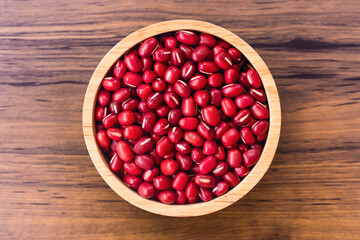 Red  Azuki beans ( Adzuki or japanese red bean ) in wooden bowl isolated on wood table background. Top view. Flat lay.