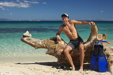 Man is standing with flippers for snorkling on the beautiful Caribbean beach 