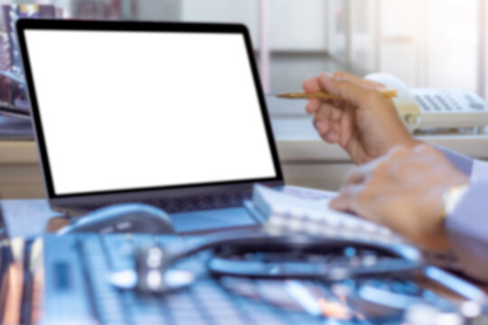 Blurred image of doctor work on blank screen laptop computer with medical stethoscope on the desk at office. Telehealth, telemedicine, e health,emr or ehr concept.