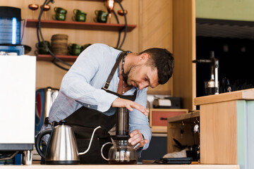 Aeropress coffee: barista press to device and coffee drops pours trought aeropress to pot....