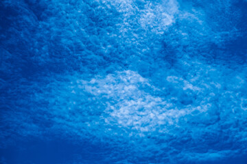 Background of lovely blue sky with altocumulus clouds scattered all over. Abstract blue background.
