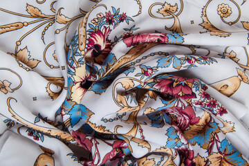 top view closeup on crumpled white cotton scarf with colorful floral ornament