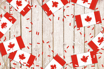 Little Canada flags and confetti on an old table. Red and white. Canada Day celebration.