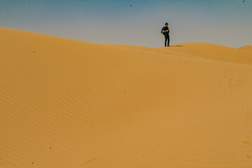 Fototapeta na wymiar A young tourist standing on the desert at Merzouga, Morocco