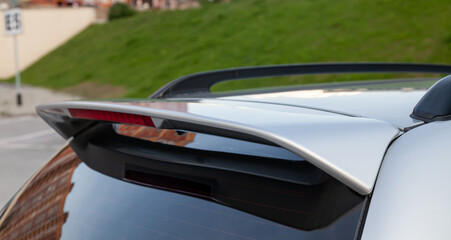Close-up on the trunk lid of a gray car with a plastic spoiler over the rear window to improve the aerodynamics of the car body during tuning for racing.